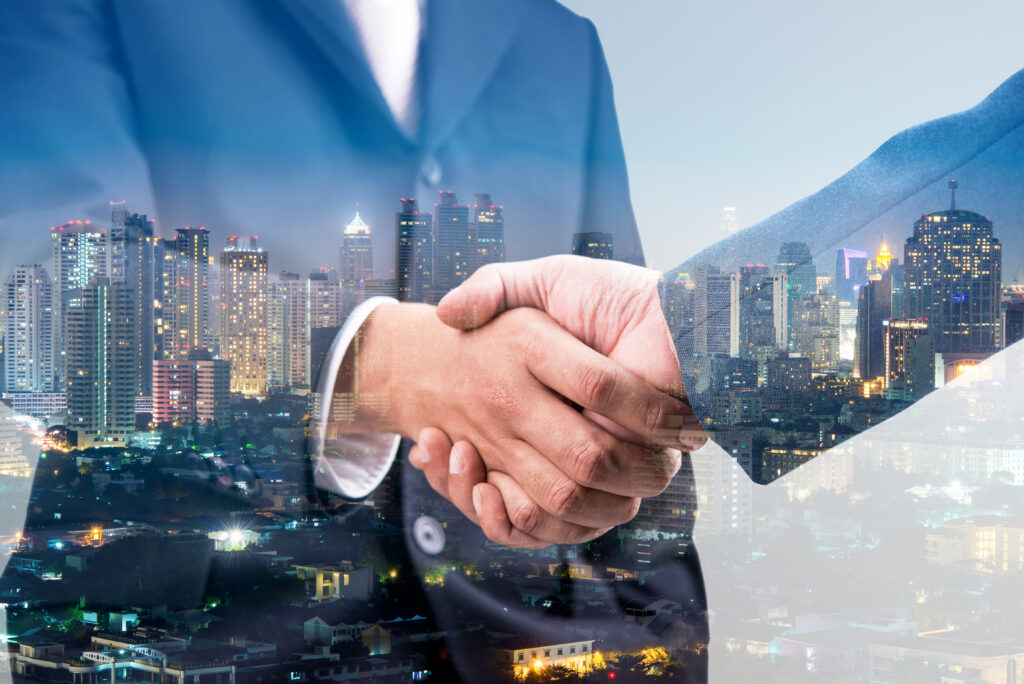 Small Business Restructuring: A New Regime. Photo of two people shaking hands set on a faded background of a city skyline